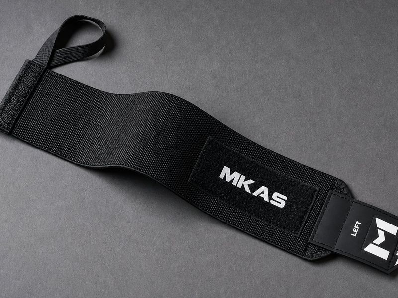 Wrist wrap construction detail showing bartack reinforcement at the thumb loop anchor, woven elastic and hook-and-loop closure